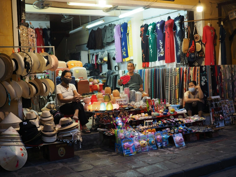 a man sitting in front of a store filled with hats